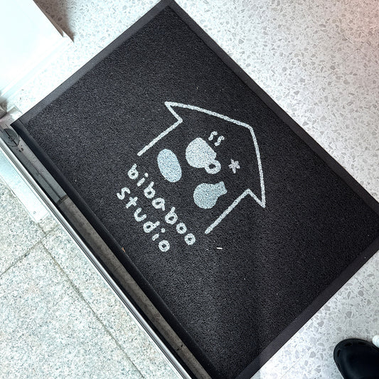 Coil 12 mm custom logo mat with a white logo on a black coil surface and rubber border, lying at a studio entrance, customer photo