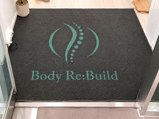 Coil 12 mm custom logo mat with a teal logo at the entrance of a wellness studio, customer photo