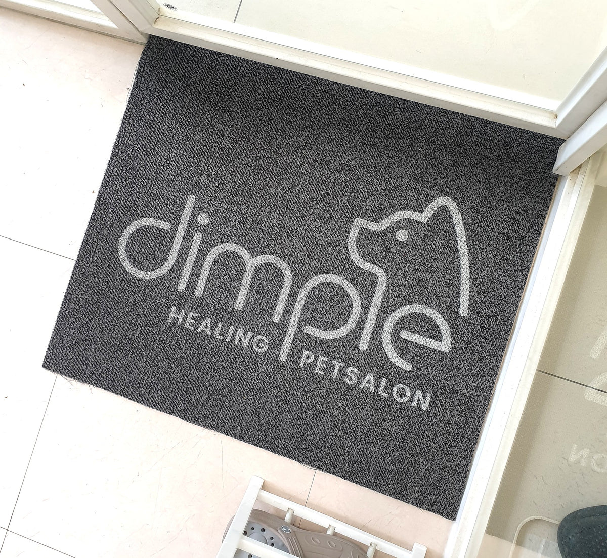 Loop 7 mm custom logo mat in dark gray with a large white logo on a bright tile floor, customer photo