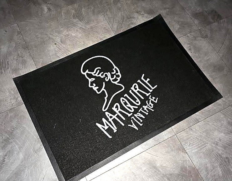 Loop 7 mm custom logo mat in black with a white line-art logo on a gray tile floor, customer photo